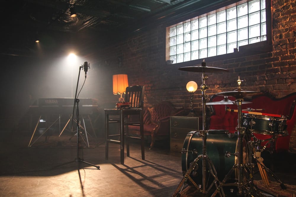 A warmly lit recording studio with a keyboard, microphone and drum kit